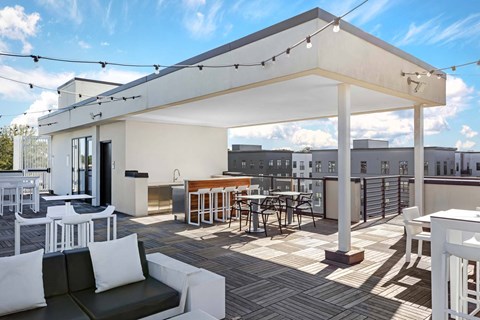 A white patio with a black couch and a table with chairs.