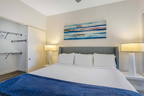 A bedroom with a large bed and a painting on the wall.