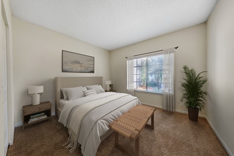 A bedroom with a bed, nightstand, and window.