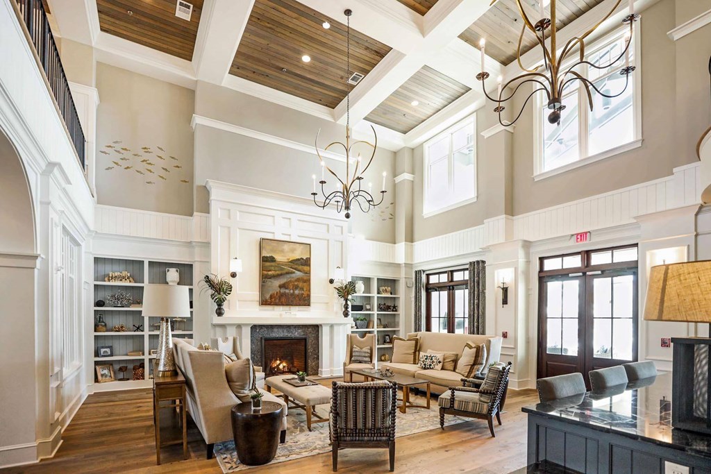 A large, well-furnished living room with a fireplace and a chandelier at Wharf 7 Apartments, Charleston, SC 29492