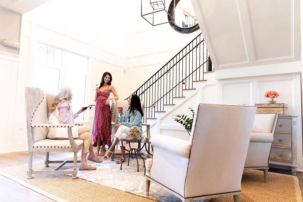 A woman in a pink dress is sitting on a white chair in a room with a staircase at Wharf 7 Apartments, Charleston, SC 29492