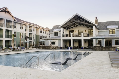 A large swimming pool in front of a resort style building.