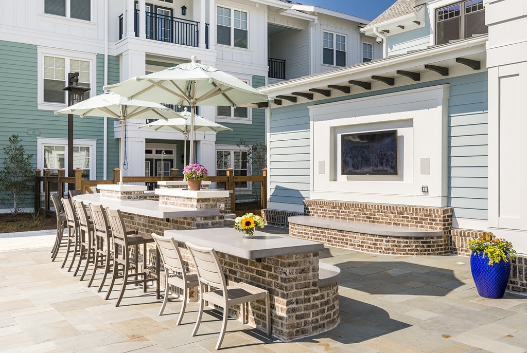 A patio with a table, chairs, and an umbrella at Wharf 7 Apartments, Charleston, 29492