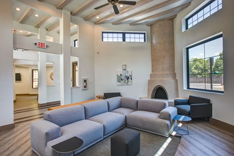 A grey couch is in the middle of a room with a fireplace and a large window.