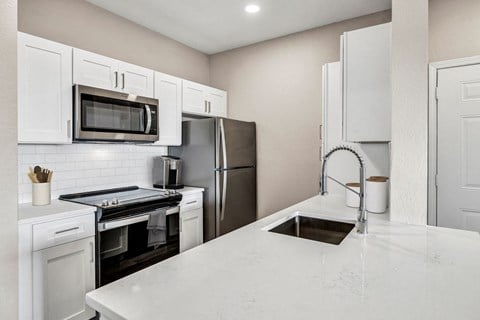 a kitchen with white cabinets and stainless steel appliances at Stonelake at the Arboretum, Austin, TX, 78759