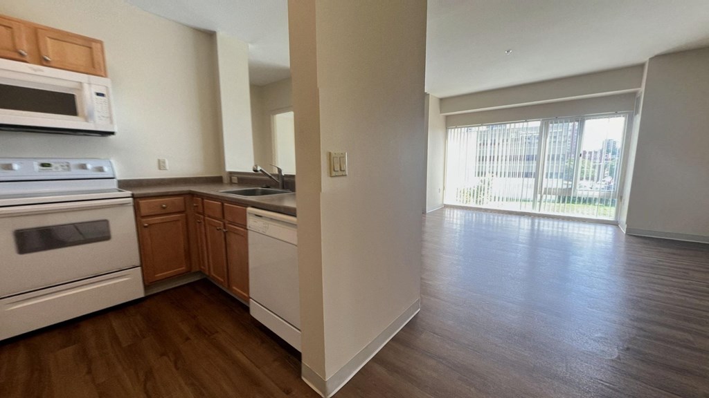 an empty kitchen and living room with wood flooring and a window