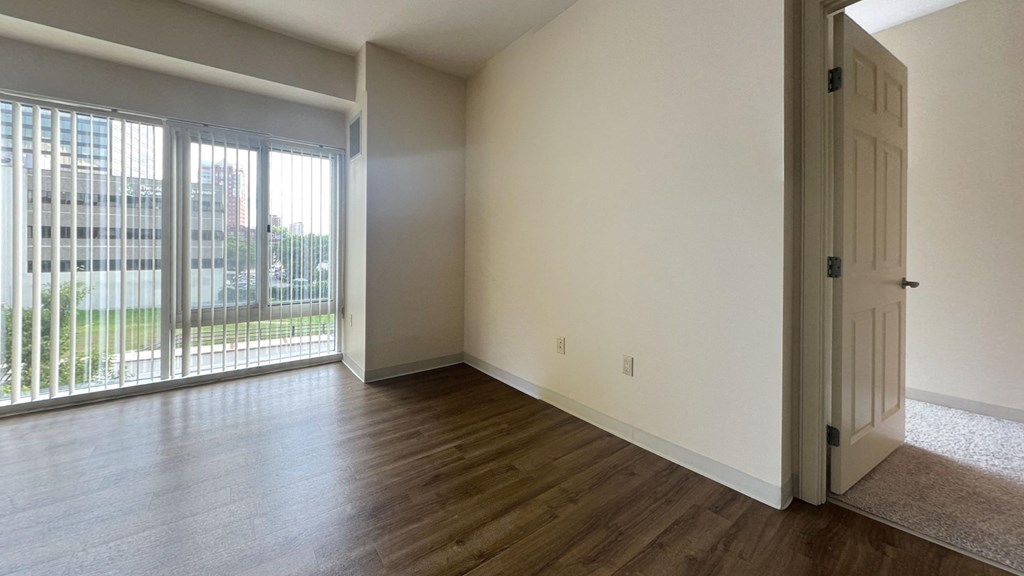 an empty living room with wood flooring and a window
