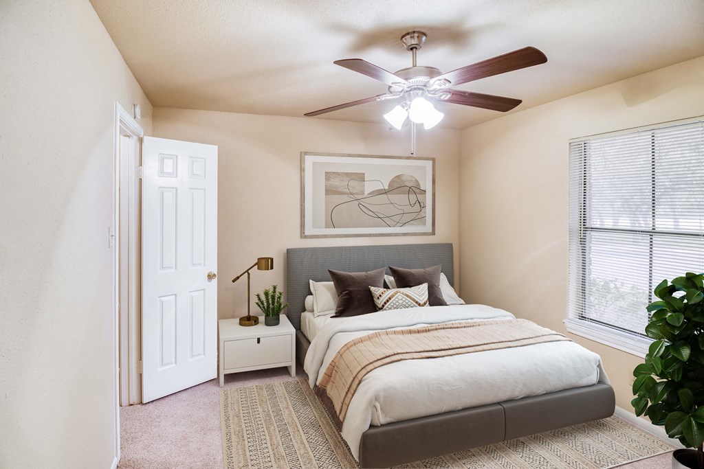 a bedroom with a large bed and a ceiling fan a bedroom with a large bed and a ceiling fan at Village Oaks Apartments, Texas, 78759
