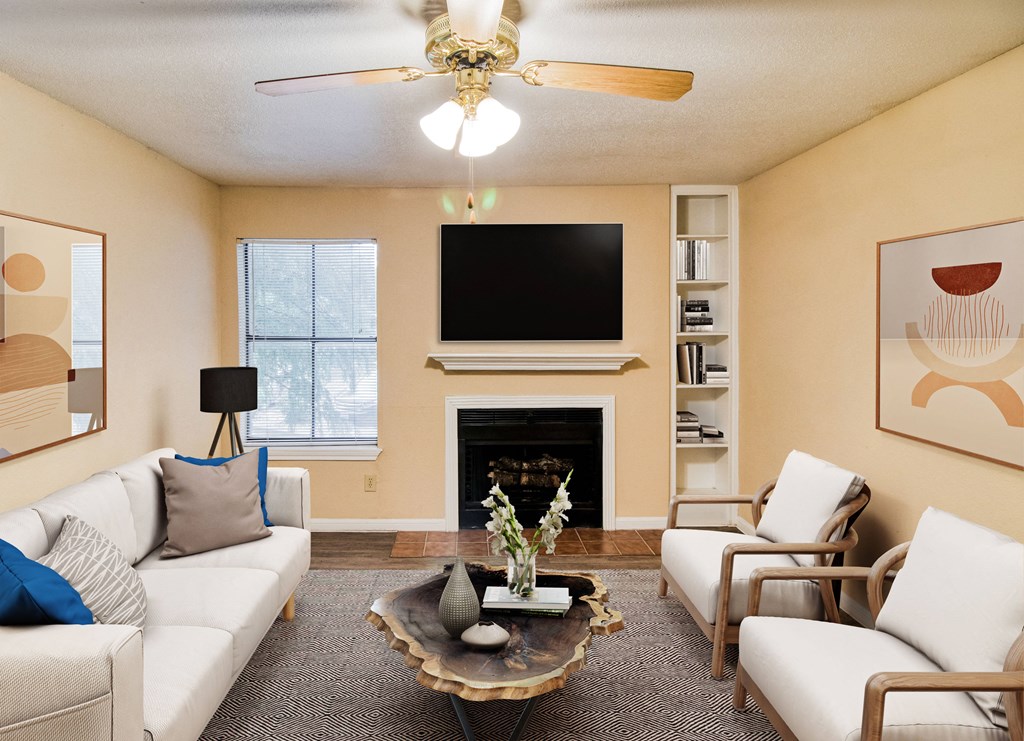 a living room with white couches and chairs and a fireplace with a flat screen tv above at Village Oaks Apartments, Austin, Texas