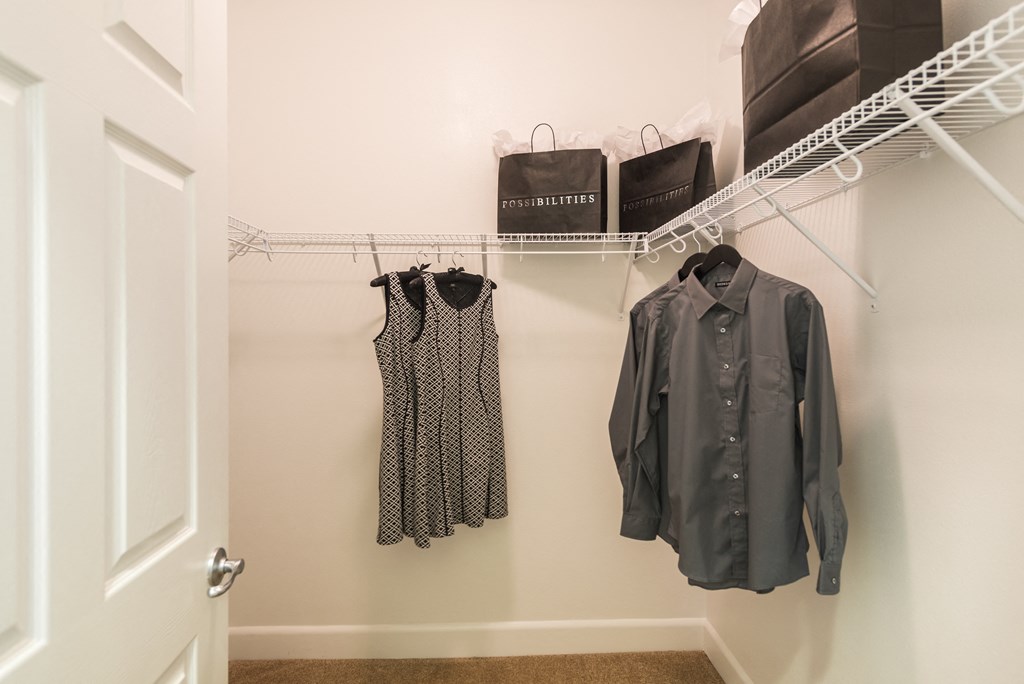 a closet with clothes hanging on a rack and a door at Estate at Woodmen Ridge, Colorado Springs