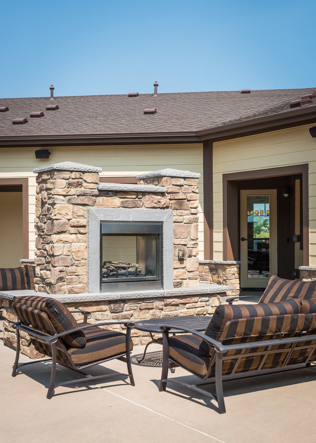 a patio with chairs in front of a building with a fireplace at Estate at Woodmen Ridge, Colorado, 80923