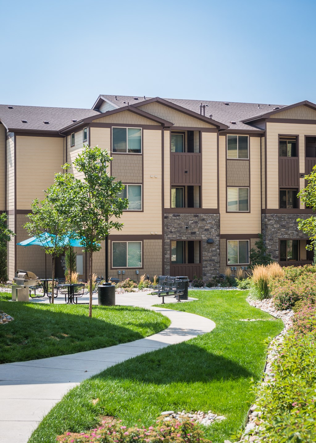 a sidewalk leading to an apartment building with a picnic table at Estate at Woodmen Ridge, Colorado Springs, CO