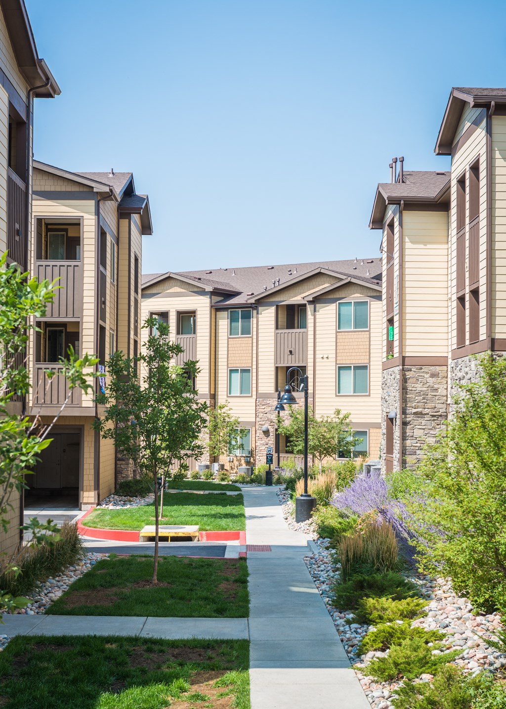 an apartment building with a sidewalk and green grass at Estate at Woodmen Ridge, Colorado Springs, CO 80923