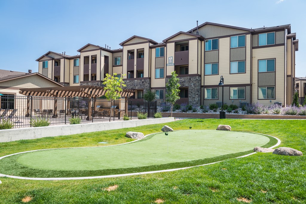 an artificial turf putting green with an apartment building in the background at Estate at Woodmen Ridge, Colorado Springs, 80923