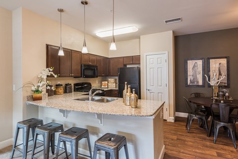 an open kitchen and dining area with stools and a granite counter top at Estate at Woodmen Ridge, Colorado, 80923