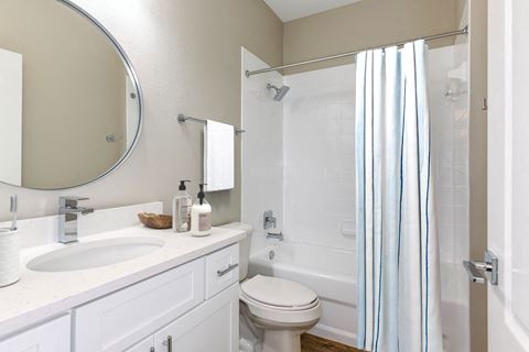 a bathroom with a white sink and toilet next to a white bathtub with a shower curtain