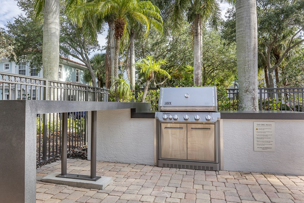 A BBQ grill is in the middle of a brick patio.