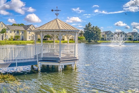 a gazebo on the water with a fountain in the background
