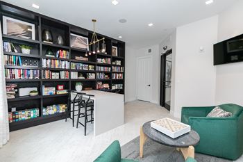 A living room with a green couch, a coffee table, and a bookshelf filled with books.