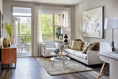 A living room with a white couch and a large painting on the wall.