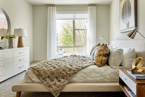 A bedroom with a bed, nightstand, and window.