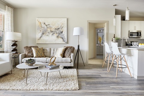 A modern living room with a white sofa and a large abstract painting on the wall.