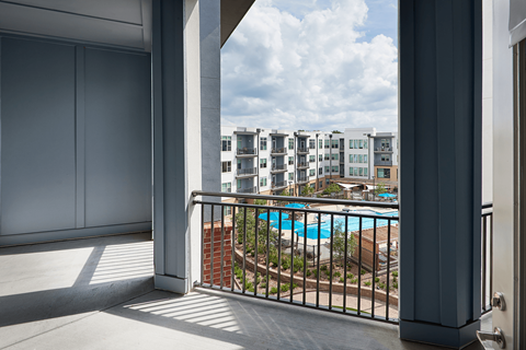 A balcony with a pool and buildings in the background.