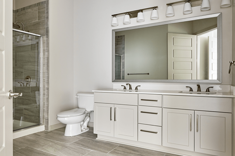 A white bathroom with a toilet, sink, and mirror.