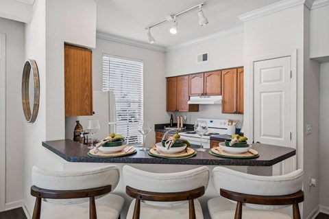 A kitchen with a table set for two with a white chair on either side.