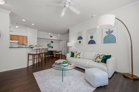 A living room with a white couch and a glass coffee table.
