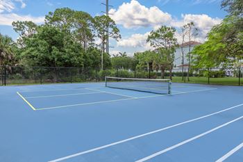 A tennis / pickleball court surrounded by trees at Floresta, Jupiter, Florida
