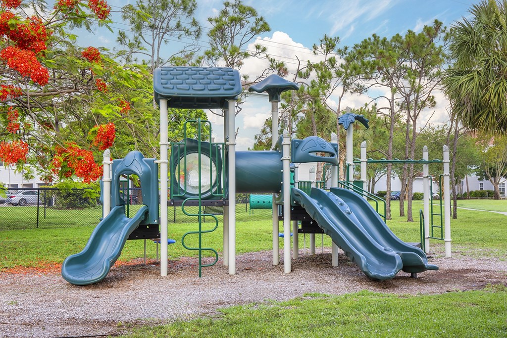 A playground with a green slide and a blue and green play structure.