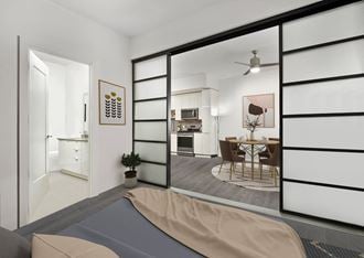 a bedroom with a bed and sliding doors that open to the kitchen and dining area