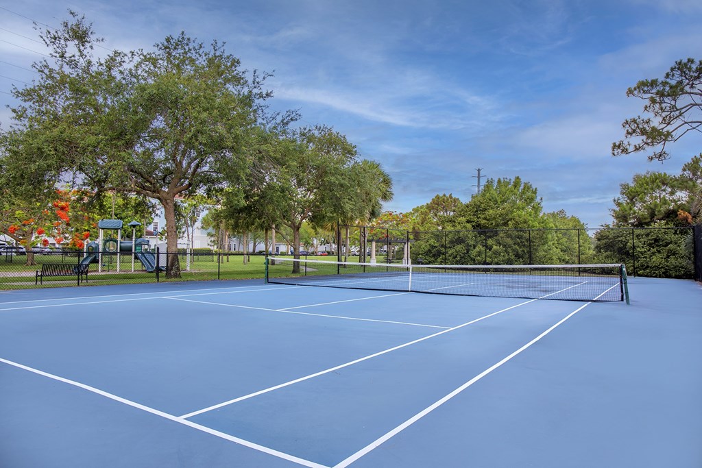A blue tennis / pickleball court surrounded by trees l at Floresta apartments in Jupiter, FL