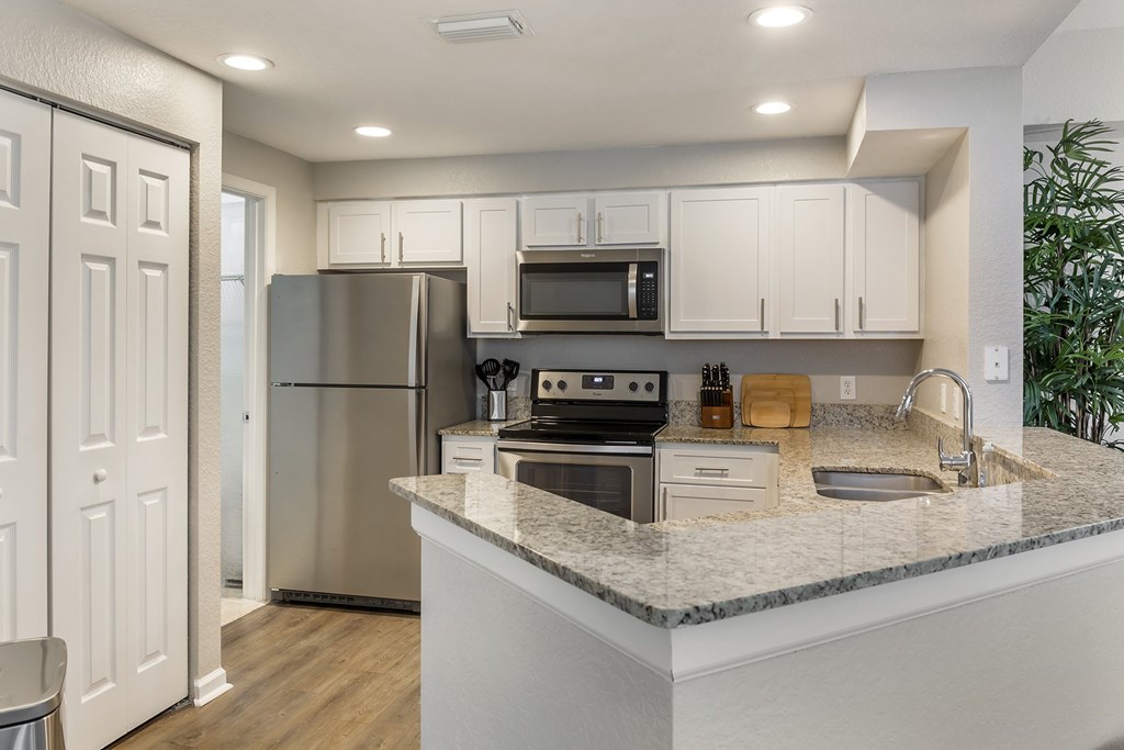 A kitchen with white countertops and stainless steel appliances at Floresta apartments in Jupiter, FL