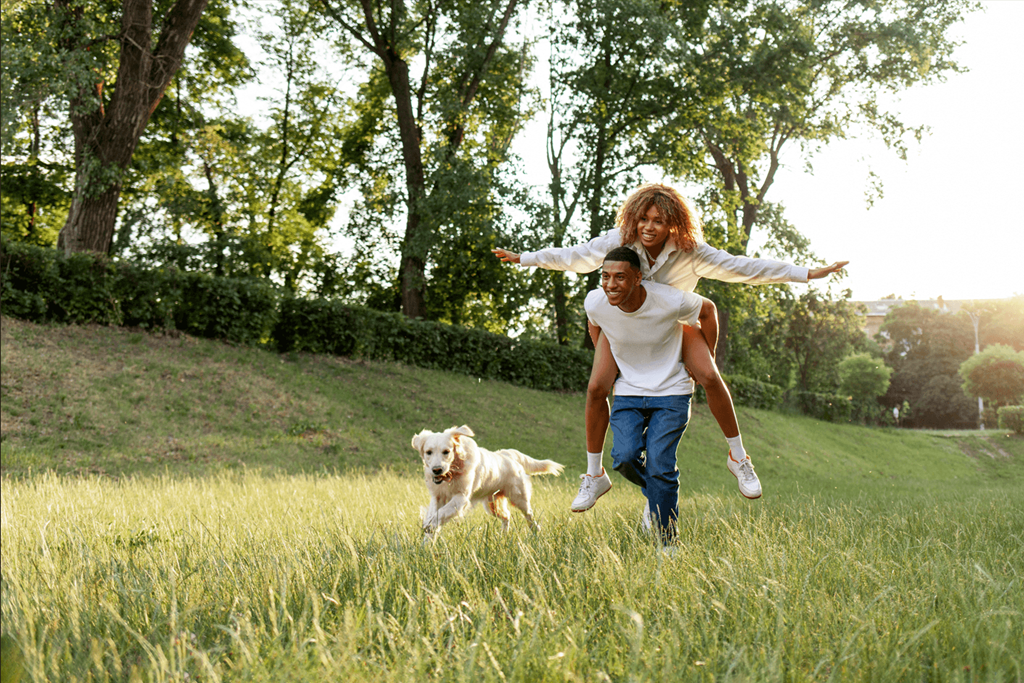 a man and woman running through a field with a dog