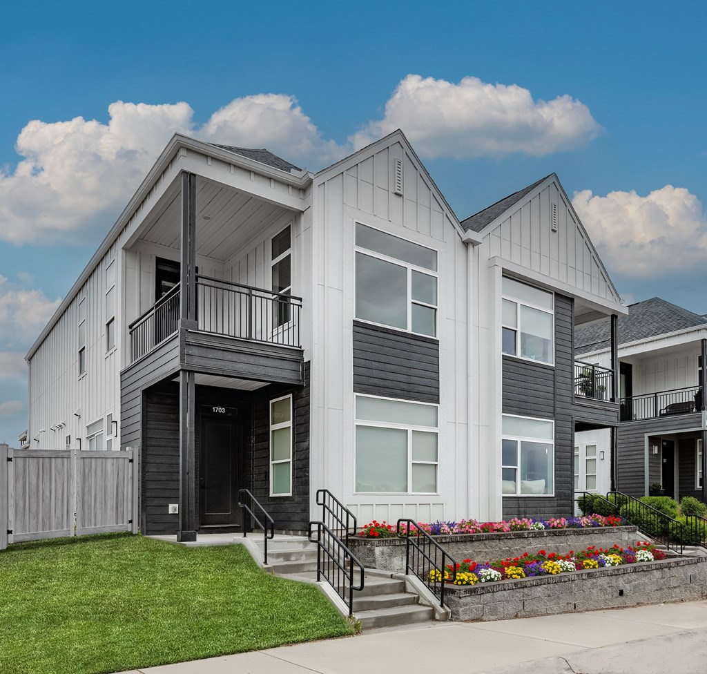 A modern two-story house with a front yard landscaped with flowers.