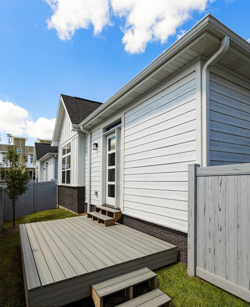 A house with a grey wooden deck and a grey fence.