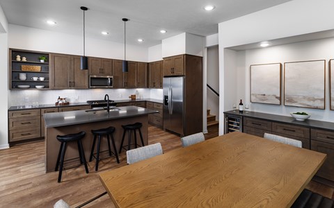 A modern kitchen with a wooden table and bar stools.