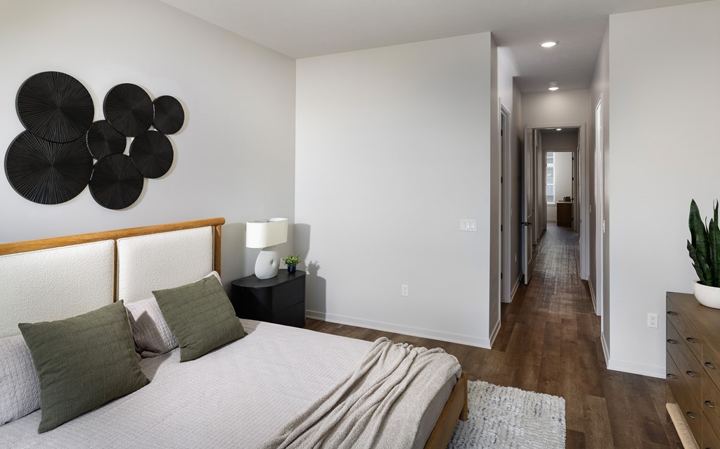 A bedroom with a bed, nightstand, and a plant.