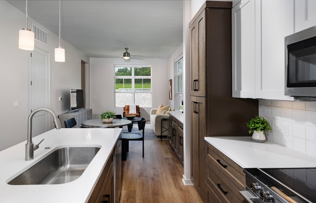 A modern kitchen with a dining area in the background.