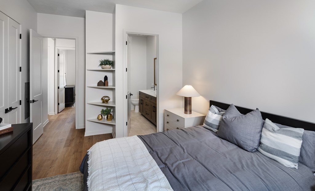 A bedroom with a bed, nightstand, and shelves.