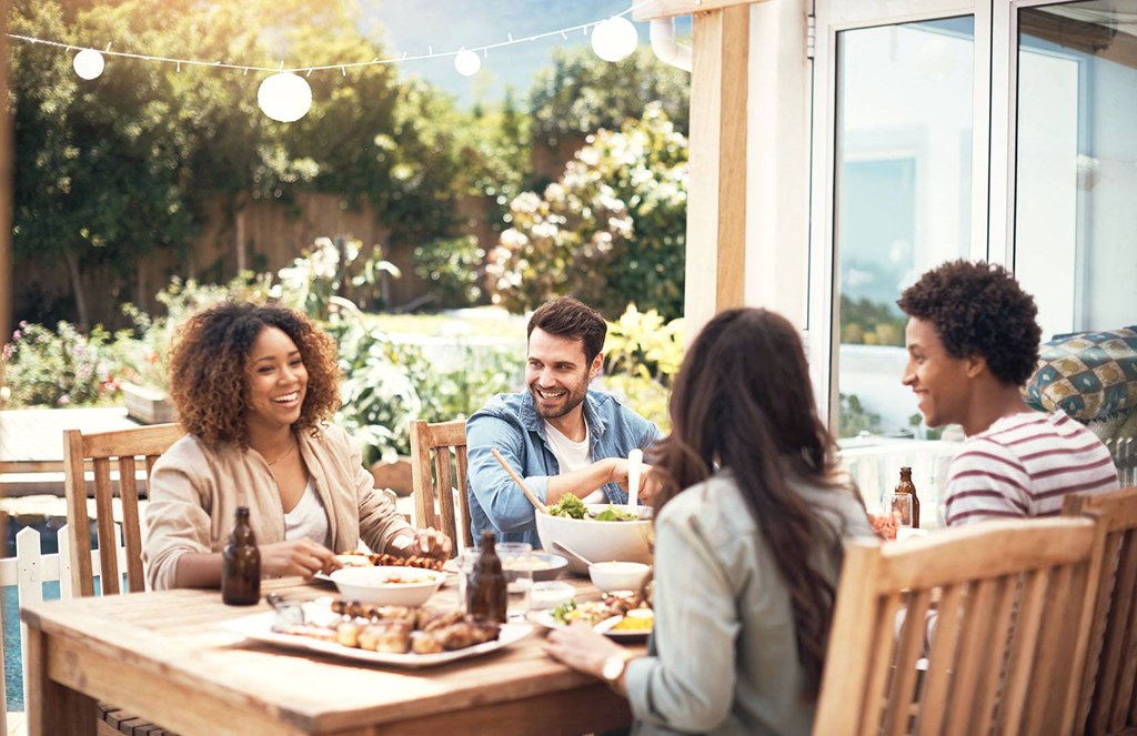 group of people sitting around a table talking and eating