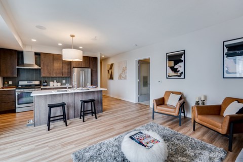 A modern kitchen with a bar area and a living room with a couch and chairs.