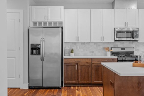 A kitchen with a refrigerator, microwave, and oven.