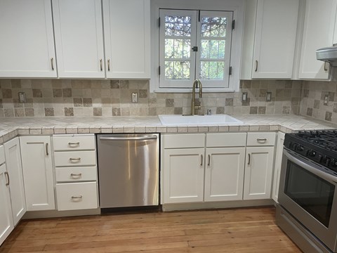 A kitchen with white cabinets and a stainless steel dishwasher.