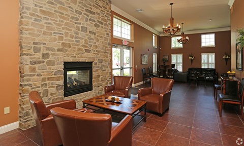 A living room with a stone fireplace and brown leather chairs.