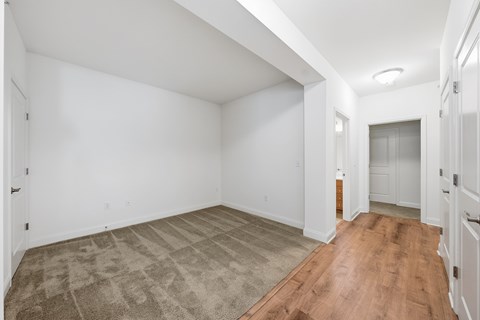 A room with a carpeted floor and wooden flooring.