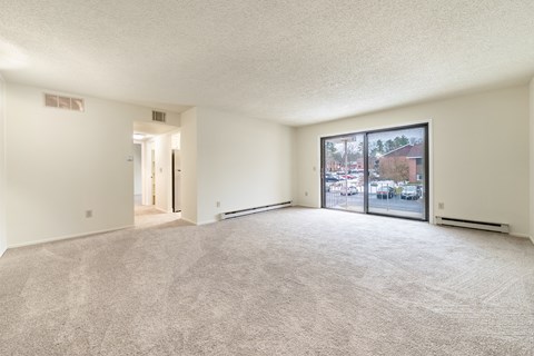 a spacious living room with a large window and carpeted flooring