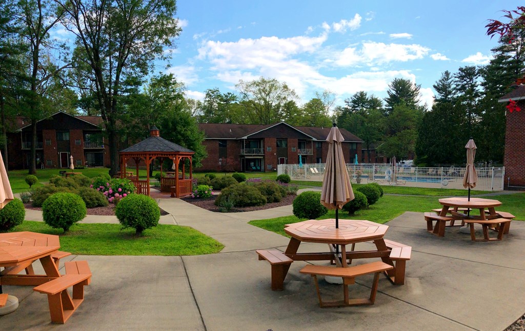 a patio with tables and benches in front of a building